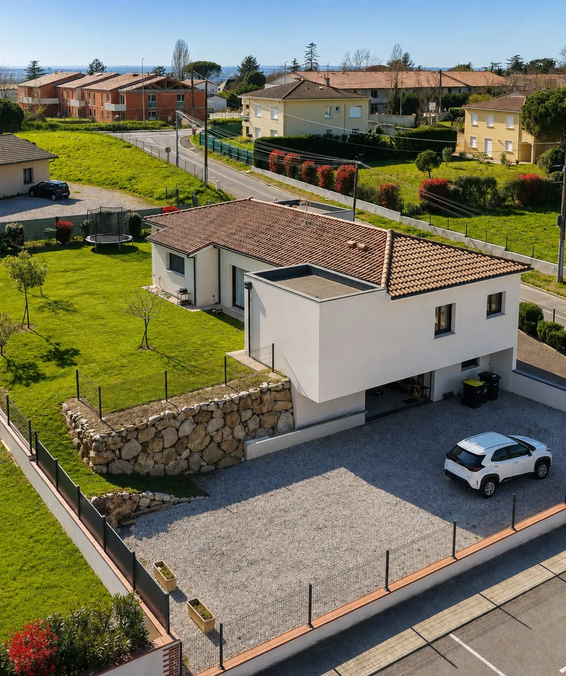 Le jardin de plain-pied et le mur en pierres sèches de la maison à étage accompagnée par GMR.