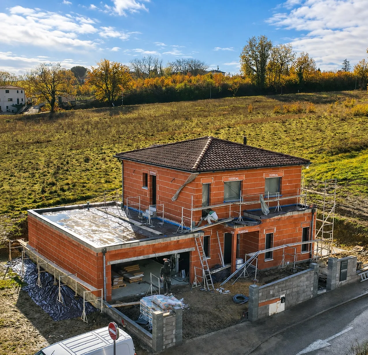 Chantier GMR en cours de gros œuvre, maison en briques et charpente terminée.